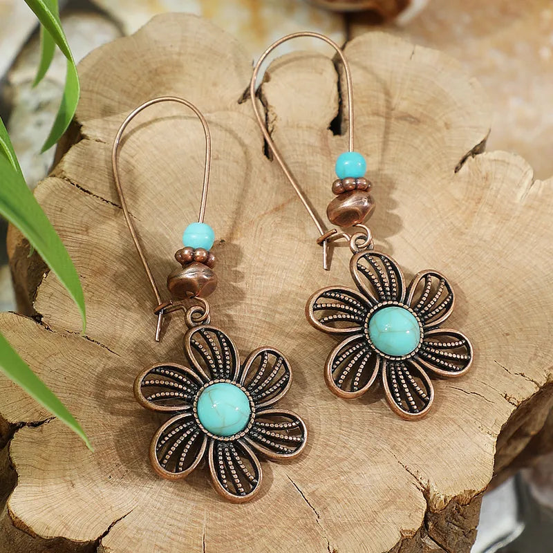 Floral earrings with turquoise stones on a wooden surface