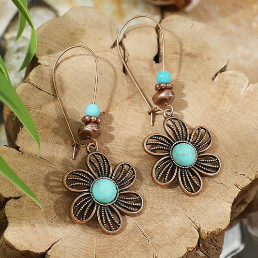 Floral earrings with turquoise stones on a wooden surface